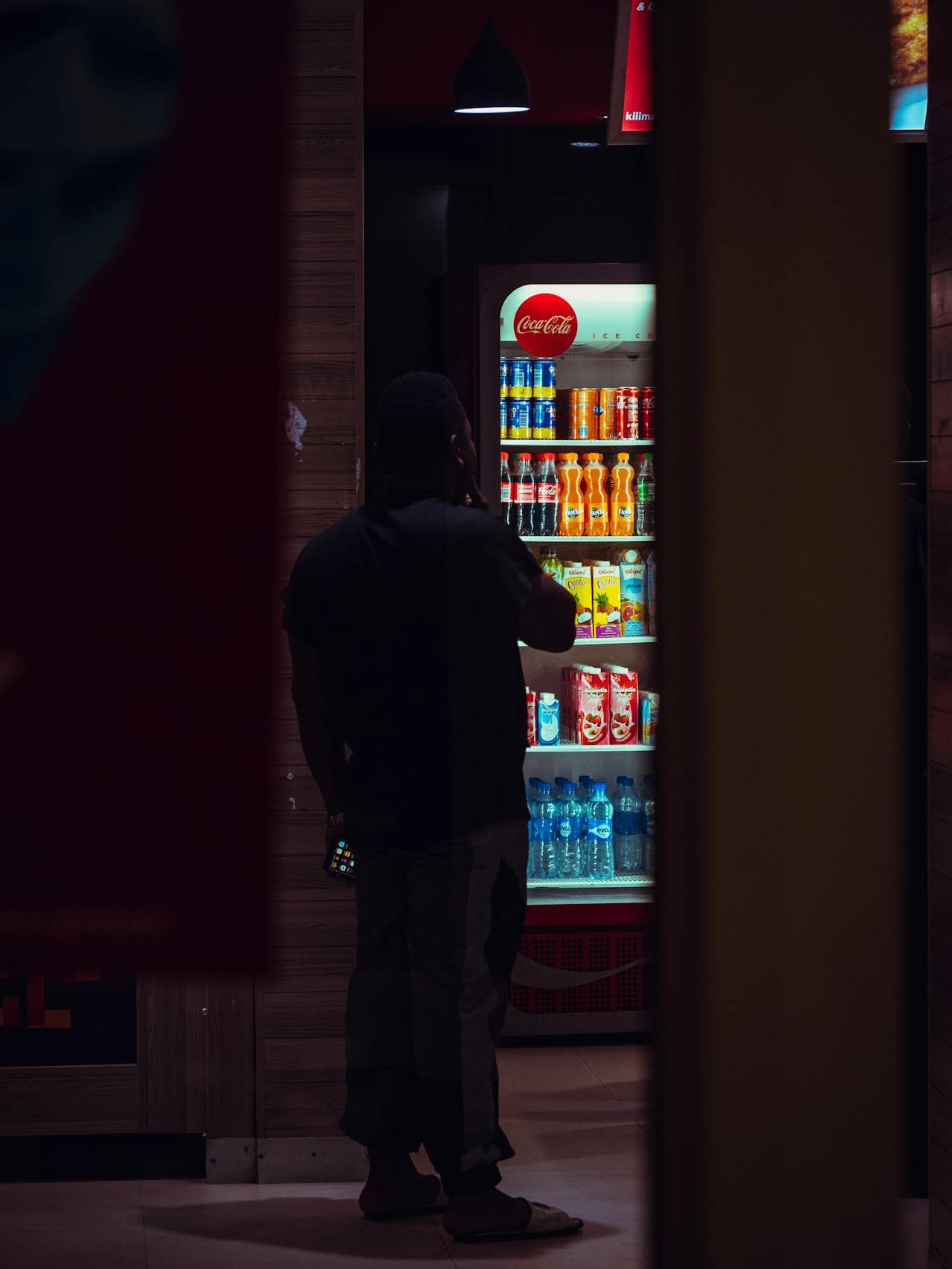Person selecting a cold beverage from a modern glass-door drink cooler